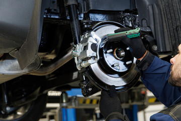 Fototapeta premium A mechanic in a car service diagnoses the brake system of a car