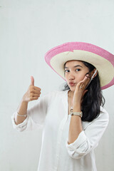 Portrait of pampered young woman in white dress and wide straw hat isolated on white background in studio with hands showing ready for holiday