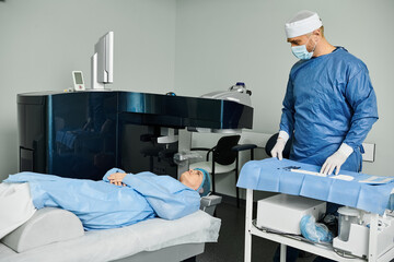 Fototapeta premium A caring man in scrubs stands by a hospital bed.