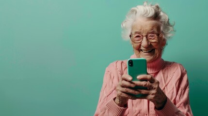 Fototapeta premium Elderly Woman Smiling with Smartphone on Mint Background - Perfect for Cheerful Commercial Banner