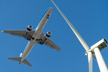 Wind turbine and plane in the blue sky