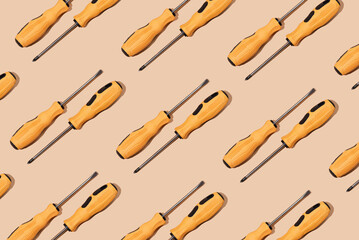 Pattern of two screwdrivers with yellow and black handle on beige background. Labor Day concept