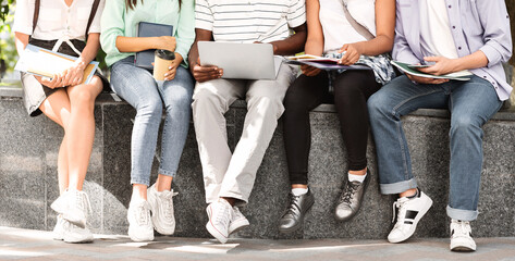 Studying Outdoors. Group of college students sitting with laptop and books, preparing for lectures together, crop