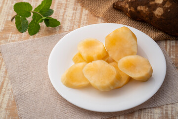 Close up peeled Yacon root fruit(Smallanthus sonchifolius) in white plate on wooden table.
