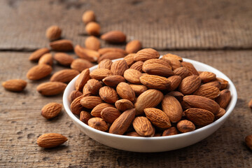 Dry roasted Almonds in white plate on wooden table.Heap of almond.