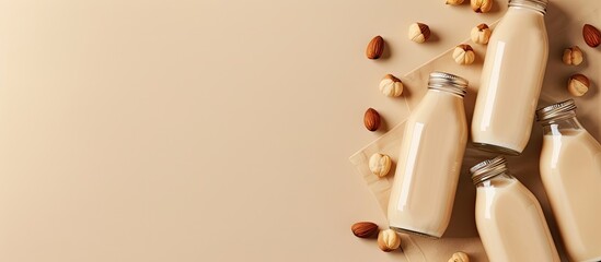 Top view of vegan hazelnut nut milk in bottles on a beige table background with copy space image, promoting a healthy vegetarian food and drink concept.