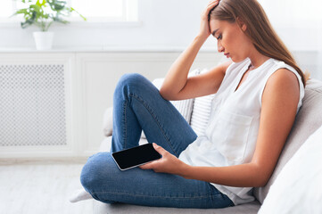 Sad Millennial Girl Holding Cellphone Waiting For Important Call Sitting On Couch At Home. Selective Focus
