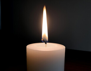 A white candle lit in a dark room. Lighting the room without electricity.