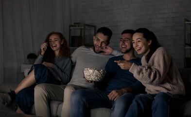 Happy friends watching comedy film and laughing, relaxing at home together