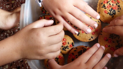 Children's hands grabbing homemade muffins from a bowl 1.