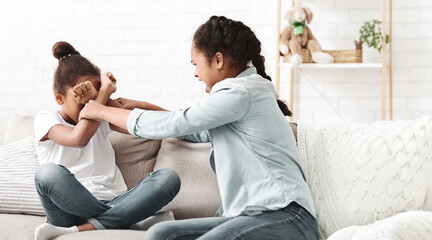 Two teenaged african girls fighting at living room, sisterhood conflict, copy space
