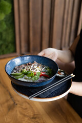 Young asian woman holding soup with beef