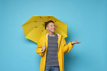 Young man with yellow umbrella on light blue background © New Africa