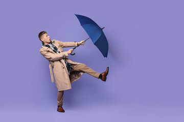 Young man with blue umbrella on purple background, space for text