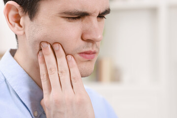 Man suffering from toothache at home, space for text