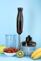 Hand blender kit, fresh fruits and strawberries on light blue background