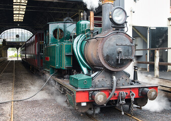 Old steamtrain waiting in the station. Old, ancient steam powered train ready to leave the station. Steam train beeing filled with water for the next trip. Small and old steam powered locomotive.