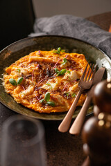 Omelete with cheese and herbs on top. Restaurant brunch.