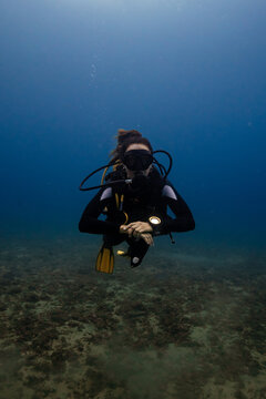 Female diver exploring underwater, looking at camera