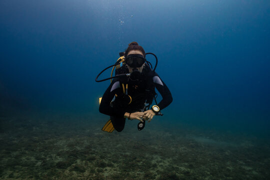 Female diver exploring underwater in clear blue water