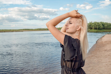 A girl on the shore in a swimsuit and a black cape.