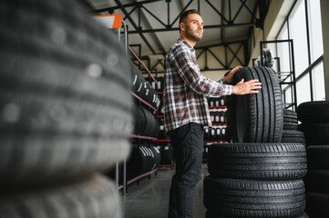 Portrait young man customer examining brand and product characteristics while buying new tires in auto department of dealership.