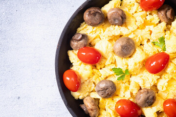 Homemade scrambled eggs with mushrooms and cherry tomatoes
