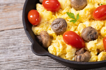Homemade scrambled eggs with mushrooms and cherry tomatoes