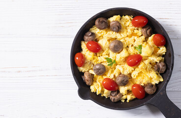 Homemade scrambled eggs with mushrooms and cherry tomatoes