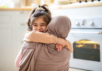 Mother's Day Concept. Cheerful Little Girl Hugging Tight Her Muslim Mom In Hijab, Islamic Woman...
