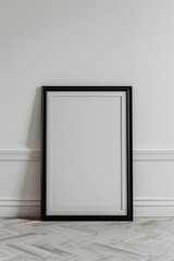 A minimalist, black-framed picture frame resting against a light beige wall in a modern, serene room.