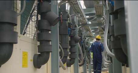 Civil engineer manager and foreman worker checking industry cooling air conditioner water cooling tower air chiller of large industrial building to control air system at construction site