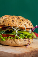 Fresh and tasty vegetarian sandwich on a wooden board with green background