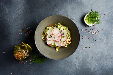 Italian pasta with cheese, pesto sauce and radish. In a plate. Top view.