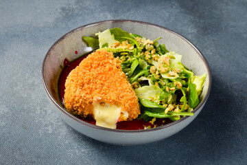 Grilled camembert cheese in breadcrumbs with vegetables. Close up.