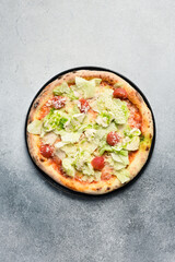 Traditional Caesar pizza. Pizza with lettuce, cherry tomatoes and sauce. Top view.
