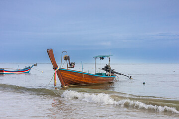 Obraz premium Colorful traditional Fishing boats in the sea near the sandy beach in Thailand. Soothing ambiance of the stunning seascape with waves and boats