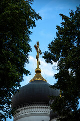 The golden cross atop the Orthodox Church dome stands out against the serene blue sky