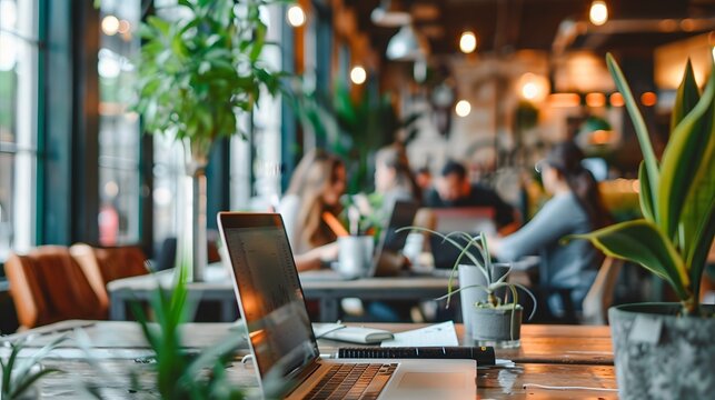 A modern, creative workspace with people collaborating on a project, using laptops and digital tablets, surrounded by inspirational quotes and plants. 