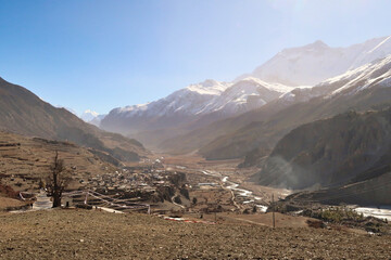 View from the trail back to the village of Gunsang, the town of Manang and the Marsyangdi River, the wind stirs up a lot of dust over the valley, Annapurna Circuit Trek, Nepal