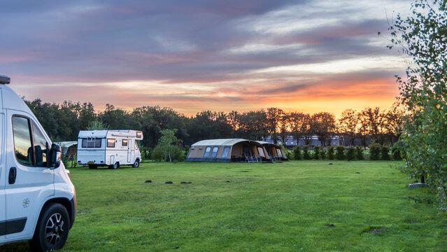Panorama landscape with beautiful sunset at farm campsite with family tents and an old camper van in Drenthe The Netherlands