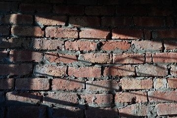 Brick wall with shadow from window grill and sunlight. Abstract industrial background for design.