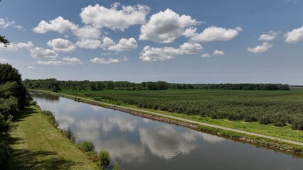 Landscape with green farmland by Eire Canal in Up State New York under blue sky and clouds on summer day