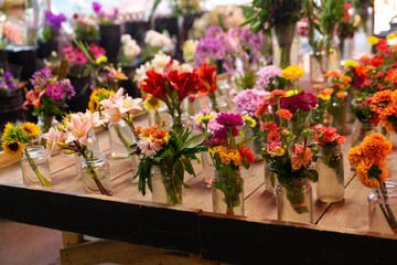 Colorful Flower Bouquets Arranged in Glass Jars on Wooden Table at Flower Market