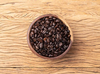 Coffee beans on a bowl over wooden table