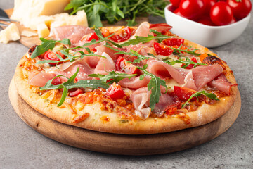 Pizza with prosciutto, ham, arugula, spinach, tomatoes, pesto, cheese and parmesan. Italian cuisine. 
