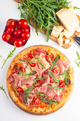 Pizza with prosciutto, ham, arugula, spinach, tomatoes, pesto, cheese and parmesan. Italian cuisine. 