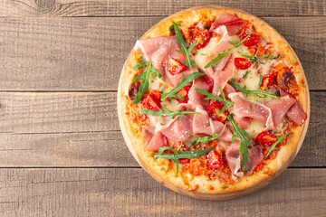 Pizza with prosciutto, ham, arugula, spinach, tomatoes, pesto, cheese and parmesan. Italian cuisine. 
