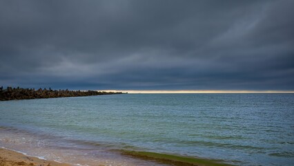 Fototapeta premium Seascape. Calm. The sky before a thunderstorm. Light on the horizon. Dramatic thunderclouds over the sea.