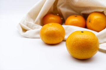 Orange fruits in a tote bag with a white background. The concept of using tote bags, eco product, and a healthy lifestyle. Orange and tote bag. Close-up ripe orange texture and fresh fruit image.